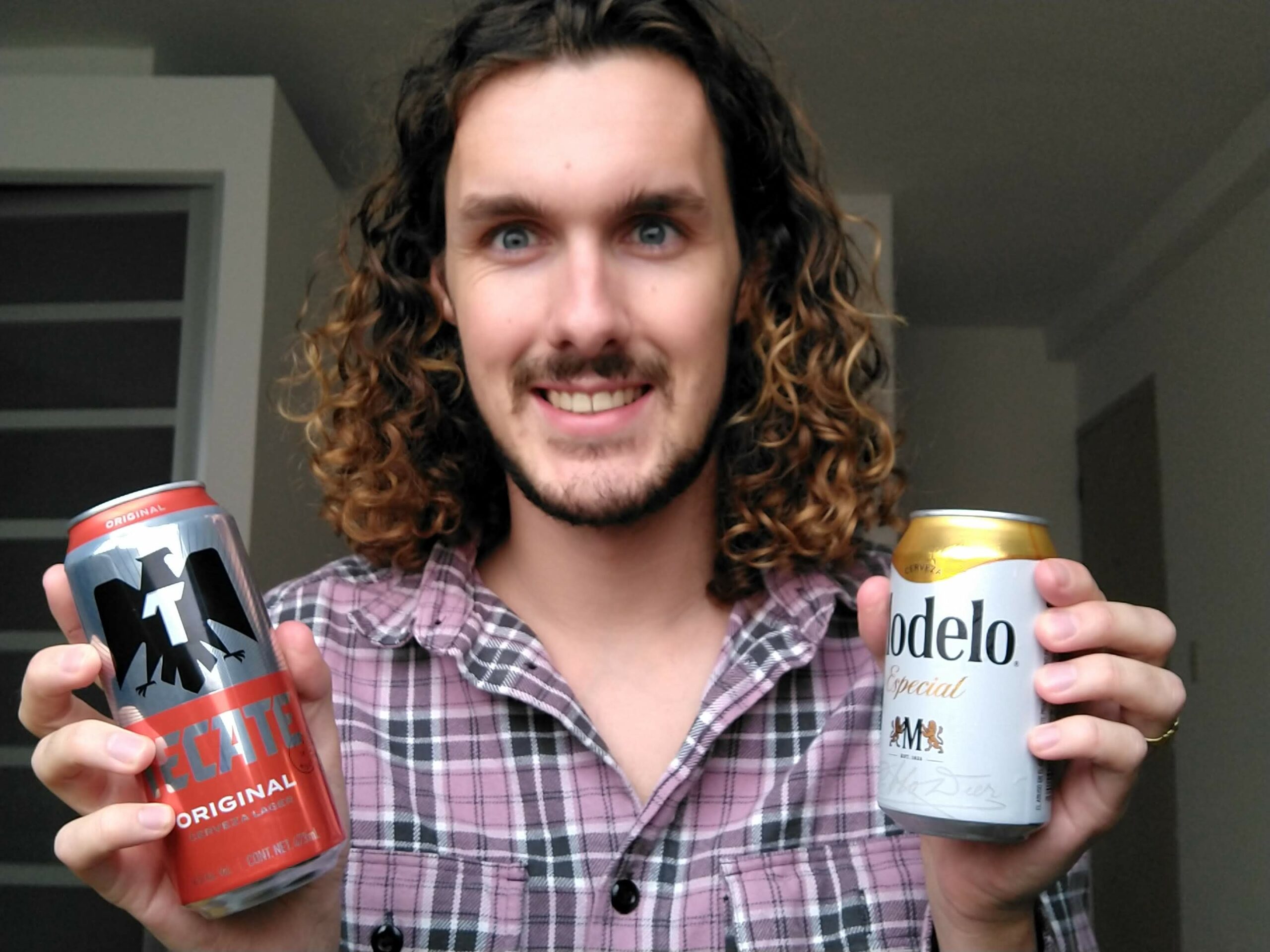 man holding cans of tecate and modelo