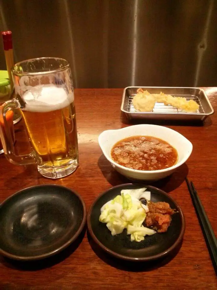 A glass of Asahi Beer next to Japanese Food