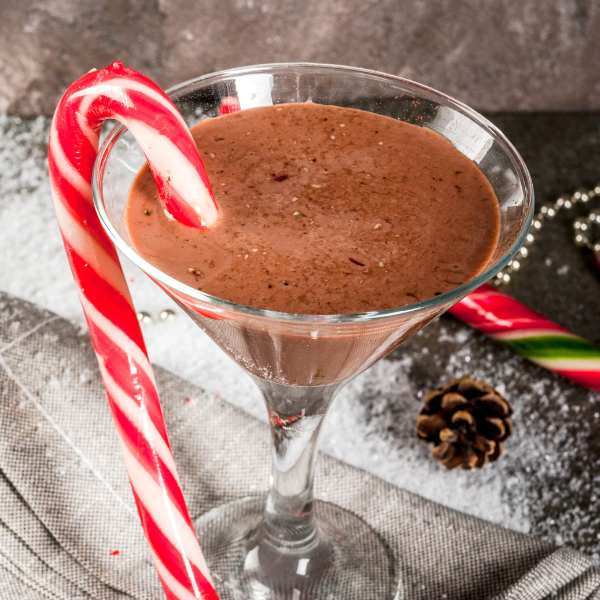 A close up of a chocholate Christmas cocktail with a candy cane garnish.